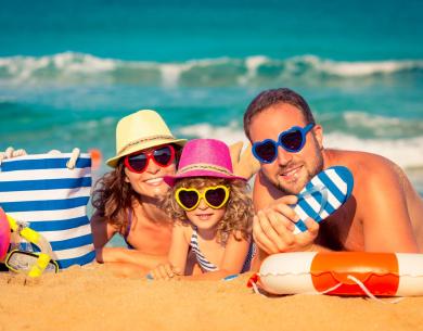 Glückliche Familie am Strand mit bunten Herz-Sonnenbrillen.