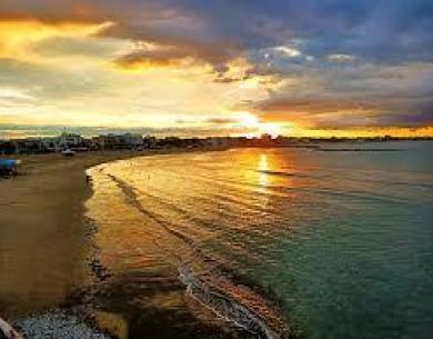 Tramonto colorato su una spiaggia sabbiosa con onde delicate.