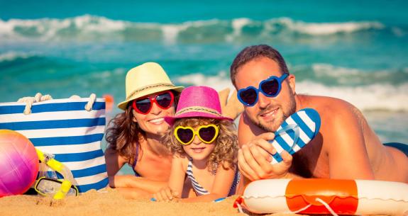 Glückliche Familie am Strand mit bunten Herz-Sonnenbrillen.