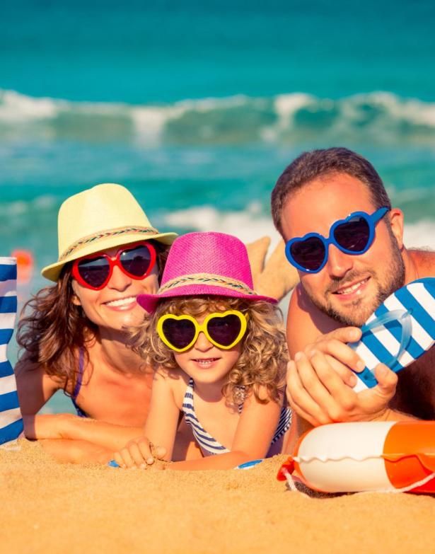 Happy family on the beach with colorful heart-shaped sunglasses.