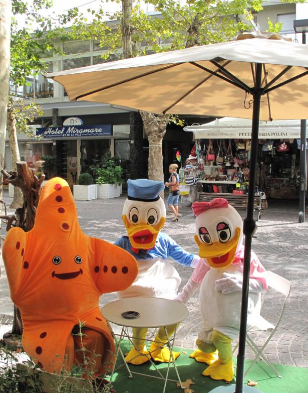 Colorful costumes sitting outdoors under an umbrella.